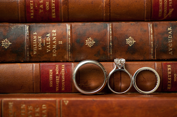 wedding rings on display sitting on book in front of a stack of other old classic books - photo by Houston based wedding photographer Adam Nyholt